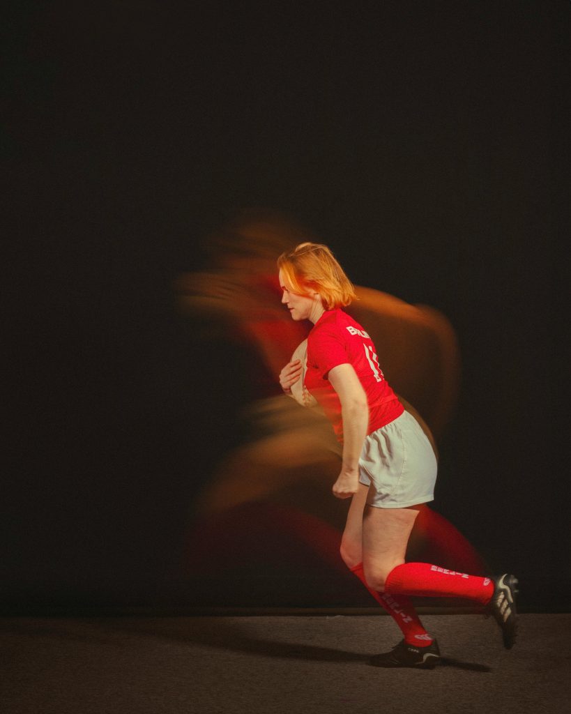 zipwp-image-30125704 Creative motion blur portrait of a female athlete in red uniform running indoors.